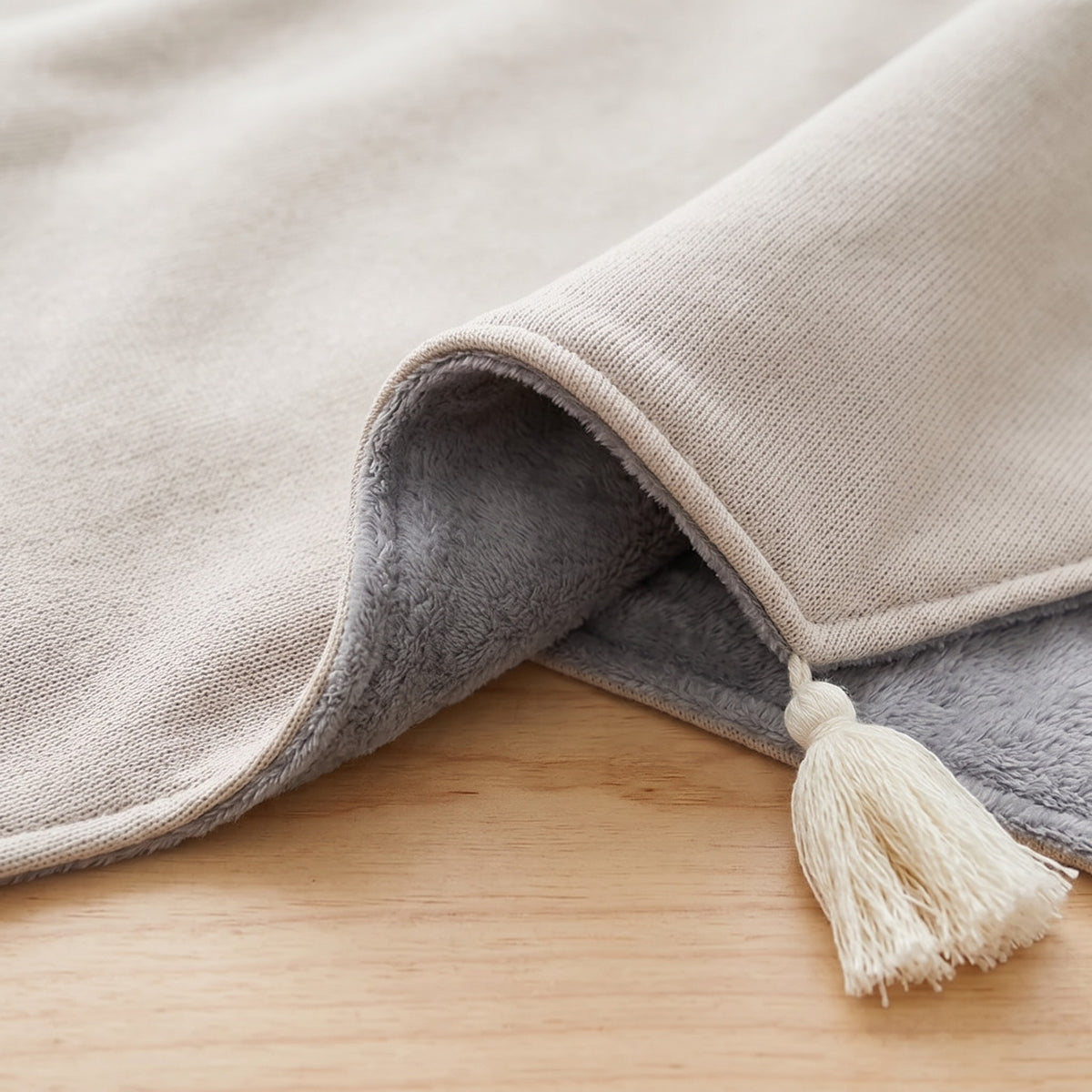 Maille sable et doublure polaire grise du poncho chauffant, pompon blanc au coin